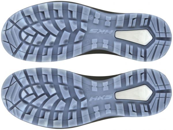 The image displays the soles of a pair of sports shoes. They feature a textured tread with rubber sections and a bright, shiny element in the center. The soles are symmetrically arranged.