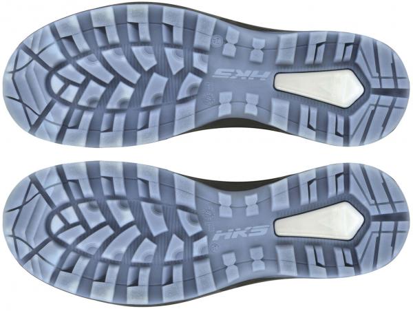 The image displays the underside of sports shoes. The sole features a textured tread with various grooves and patterns for improved grip. A prominent logo is located in the center.