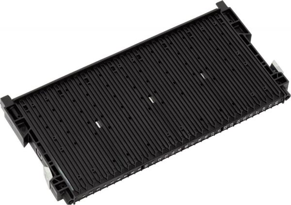 The image shows a black, rectangular component with several narrow grooves and slots. It has small protrusions on the sides and appears to be a storage or connecting element for technical devices.
