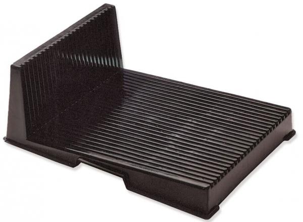 The image shows a black, rectangular object with a slanted back wall. The surface is ridged, giving it texture. It is often used as a stand or holder.