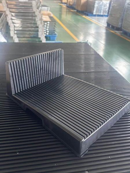 The image shows a black, rectangular block with a raised back. The surface is ridged and consists of parallel stripes. It is situated on a flat, even surface.