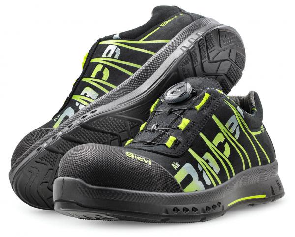 The image shows a pair of black work or sports shoes with green accents. They feature a sturdy rubber sole and an innovative quick-lace system.