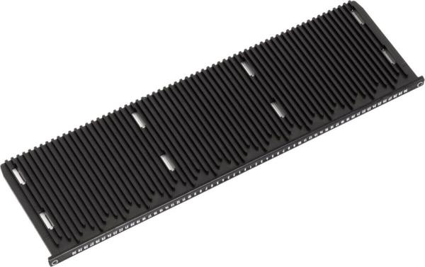 The image shows a black, elongated object with many parallel grooves. It has a smooth surface and device slots or openings at the edges.