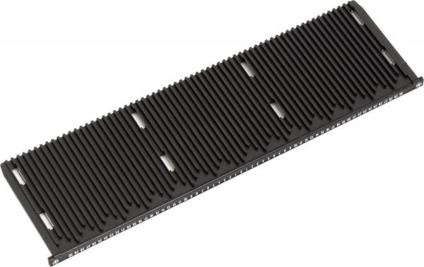 Das Bild zeigt ein schwarzes, längliches Objekt mit vielen parallelen Rillen. Es hat eine flache Form und könnte eine Art Halterung oder Ablage sein. Die Oberfläche ist strukturiert.