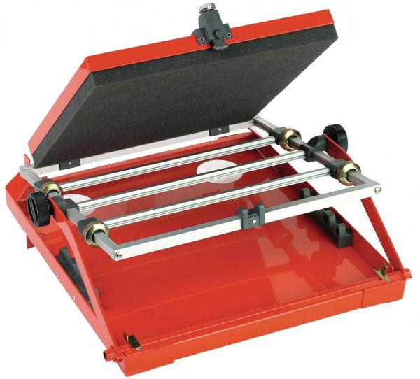 The image displays a red heat press. The upper part is foldable, featuring a black surface. On the underside, rollers and a conspicuous rail are visible.
