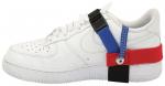 Preview: Das Bild zeigt einen weißen Sneaker mit verschiedenen farbigen Riemen: rot, blau und schwarz, die seitlich am Schuh befestigt sind. Der Schuh hat eine klassische Sneakerform mit Schnürsenkeln.