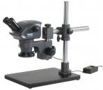 Preview: The image shows a microscope with two eyepieces on a stable stand. It has a large, round base and a switch for control. The construction is metallic and robust.