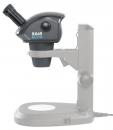 Preview: The image displays a microscope in black and gray. The upper part features a round lens and an eyepiece, while the base is flat and stable. A cable connects the microscope to a power source.