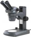 Preview: The image shows a microscope with two eyepieces, a stable base, and a round slide. It is gray in color and has several adjustment options for focusing.