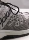 Preview: The image shows a gray sports or running shoe. It features a breathable, knitted upper with a subtle pattern and gray laces. The shoe has a light-colored sole.