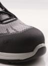 Preview: The image shows the tip of a gray shoe with a solid, black cap. The upper material is made of a loose, breathable fabric. Laces run across the shoe.