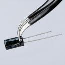 Preview: The image shows a pair of tweezers holding a cylindrical, black capacitor. The capacitor has two metal terminals and markings in white and gold.