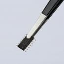 Preview: In the image, a small, rectangular chip is visible, held by tweezers. The chip has several metallic contacts on the sides and is black. The background is light.