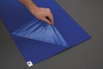 Preview: Eine Hand hebt eine transparente, gewellte Folie, die über einer blauen Fläche liegt. Die Folie hat ein dreieckiges Muster und reflektiert das Licht. Im Hintergrund ist ein grauer Untergrund.