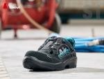 Preview: Das Bild zeigt einen schwarzen Arbeitsschuh mit blauen Akzenten. Er hat eine flache Sohle und ein schnelles Schnürsystem. Der Schuh steht auf einem grauen Boden in einer Werkstatt.