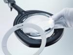 Preview: The image shows a magnifying glass with a round, clear lens. This is mounted on a black holder, while a hand wearing a white glove lifts the lens.