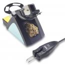 Preview: The image shows a soldering iron stand with a gold-colored soldering aid and a sponge. The soldering iron has a black grip surface and a plugged-in connection.