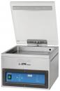 Preview: The image shows a kitchen appliance, a vacuum sealer. It has a rectangular, metallic casing with a transparent lid. On the front, there are controls and a digital display.