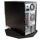 Preview: The image displays the casing of a computer. It is black with a silver back that features various ports and ventilation slots. The computer is situated on a plated base.