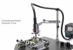 Preview: The image shows a technical device mounted on a table. A holder secures a tool with a handle, while an electric control unit is positioned next to it.