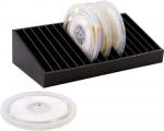 Preview: The image shows a black storage box with compartments for several transparent film reels. One reel is lying next to it. The reels are circular with a central opening.