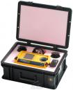 Preview: The image shows a black hard-shell suitcase that is open. Inside, there is a yellow measuring device with a screen, surrounded by cables and two round controls.