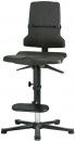 Preview: The image shows an adjustable-height, black office chair with a backrest. The seat is lightly padded, and there is a footrest as well as a base plate with five casters.
